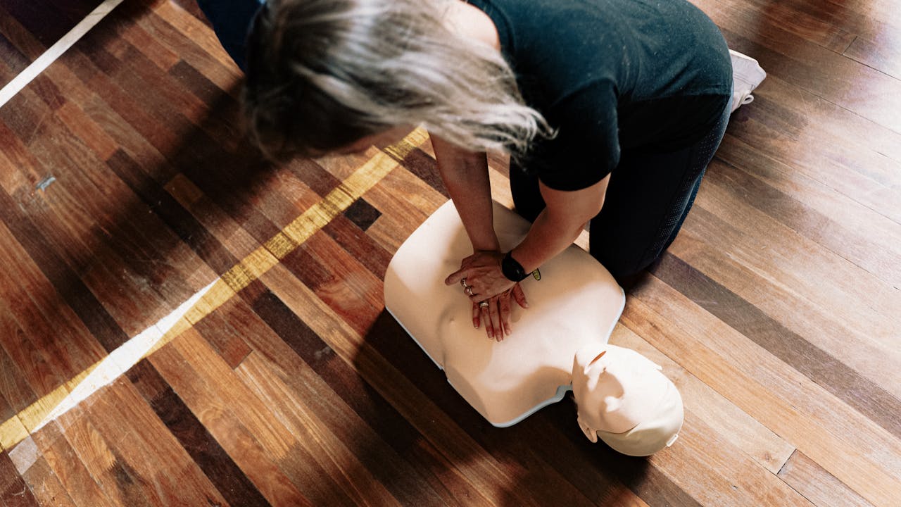 home-hero A person practices CPR on a training mannequin indoors.