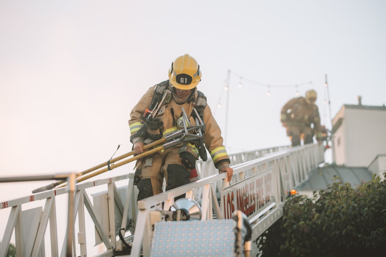 services-06 Firefighters in protective gear climbing down a ladder during a rescue operation. Teamwork in action.